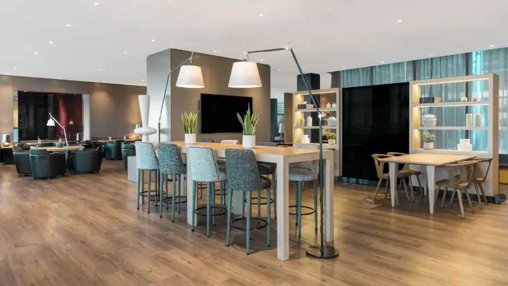 Espace de détente lumineux avec tables hautes et canapés confortables.