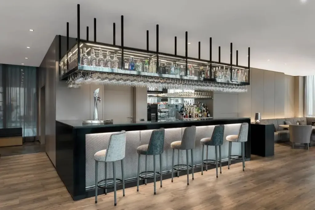 Un comptoir de bar moderne avec des tabourets et une étagère remplie de bouteilles.