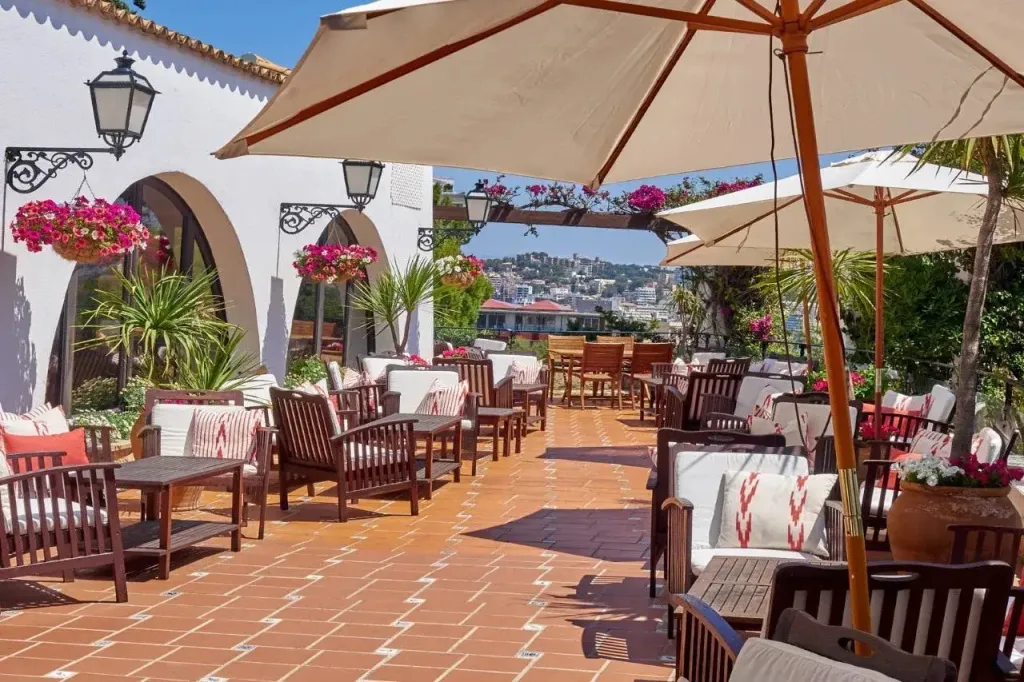 Terrasse ombragée avec mobilier de jardin et vue sur la mer.