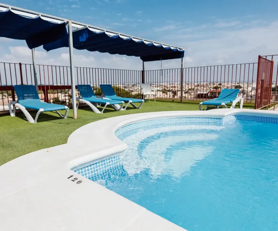 Transats bleus disposés autour d'une piscine en bord de terrasse.
