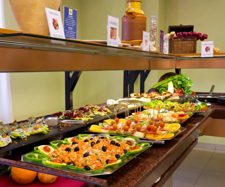 Un buffet propose une variété de salades, de viandes et de fruits.