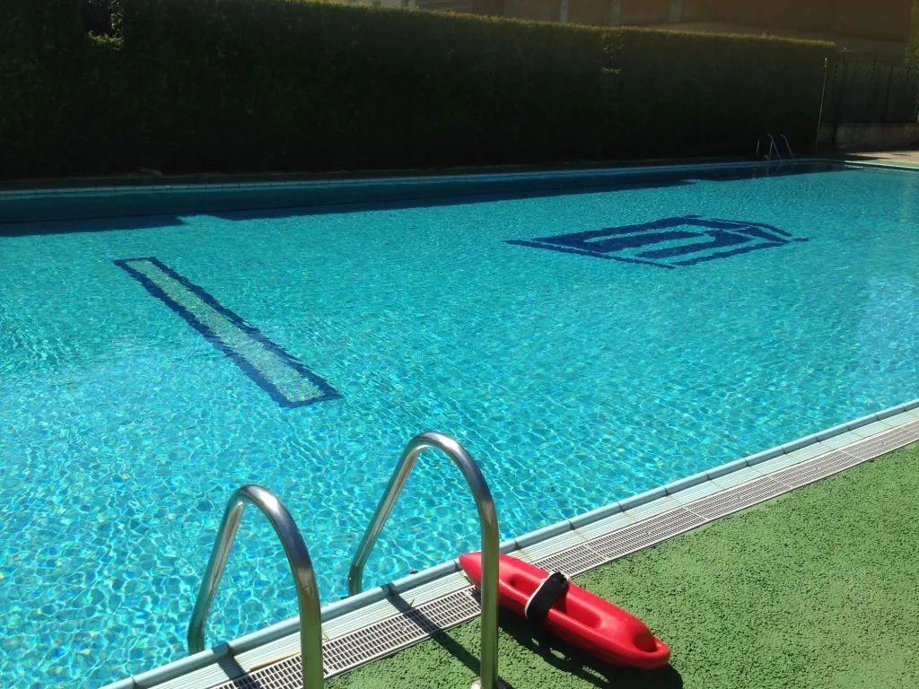 Une piscine rectangulaire avec des lignes bleues au fond et un escalier d'accès.
