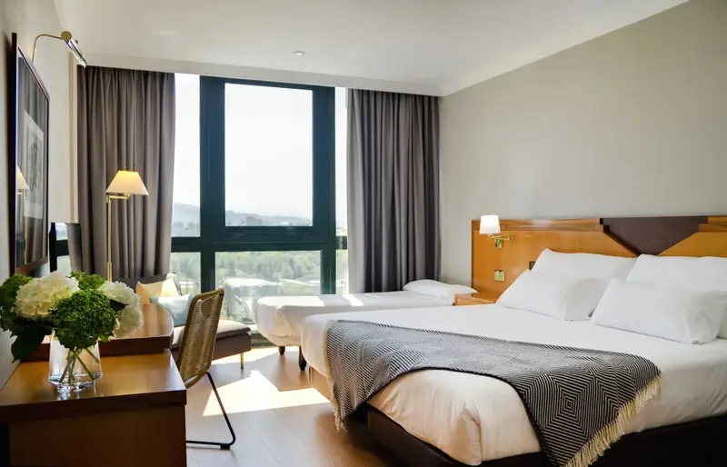 Une chambre lumineuse avec deux lits simples et une vue sur un paysage verdoyant.