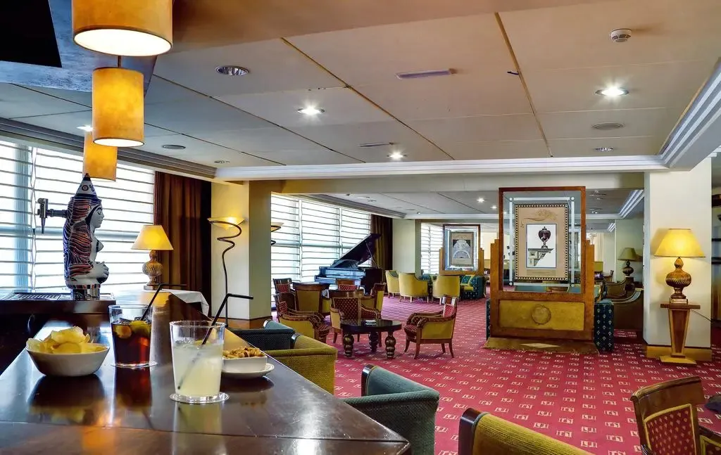 Un bar avec des boissons et des collations, dans un espace de détente avec des fauteuils et un piano.