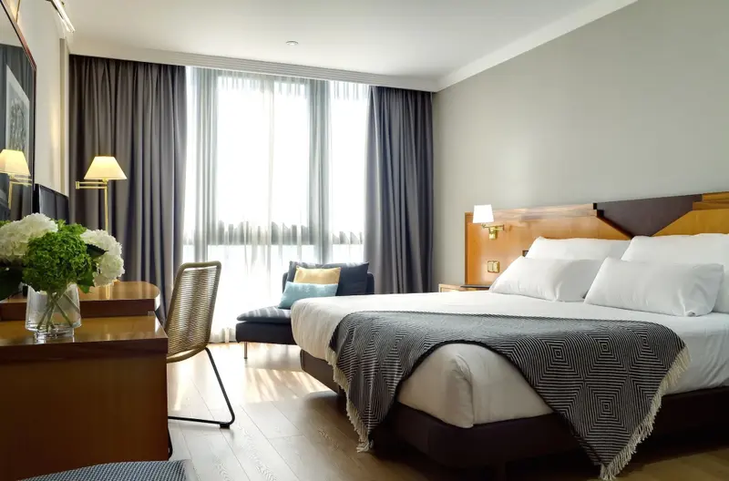 Une chambre lumineuse avec un grand lit et un coin lecture près de la fenêtre.