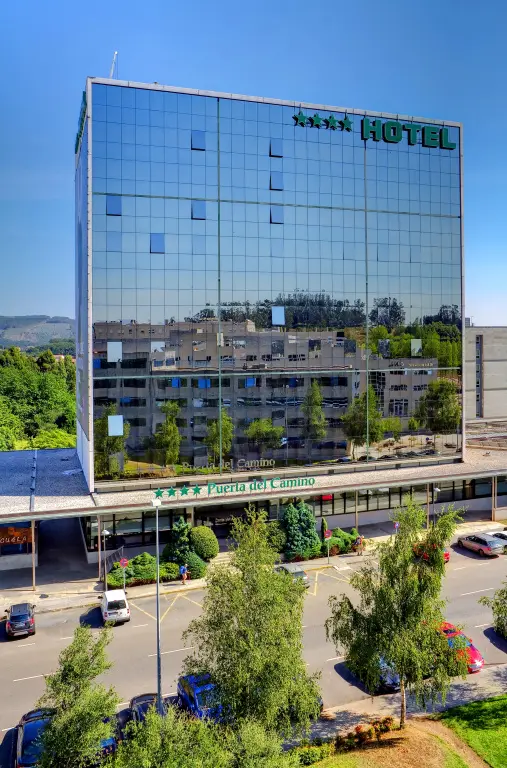Immeuble moderne avec une façade vitrée reflétant le ciel bleu et la végétation environnante.