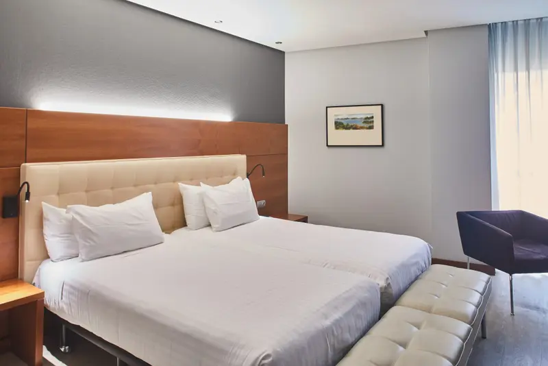 Une chambre lumineuse avec un grand lit et un fauteuil.