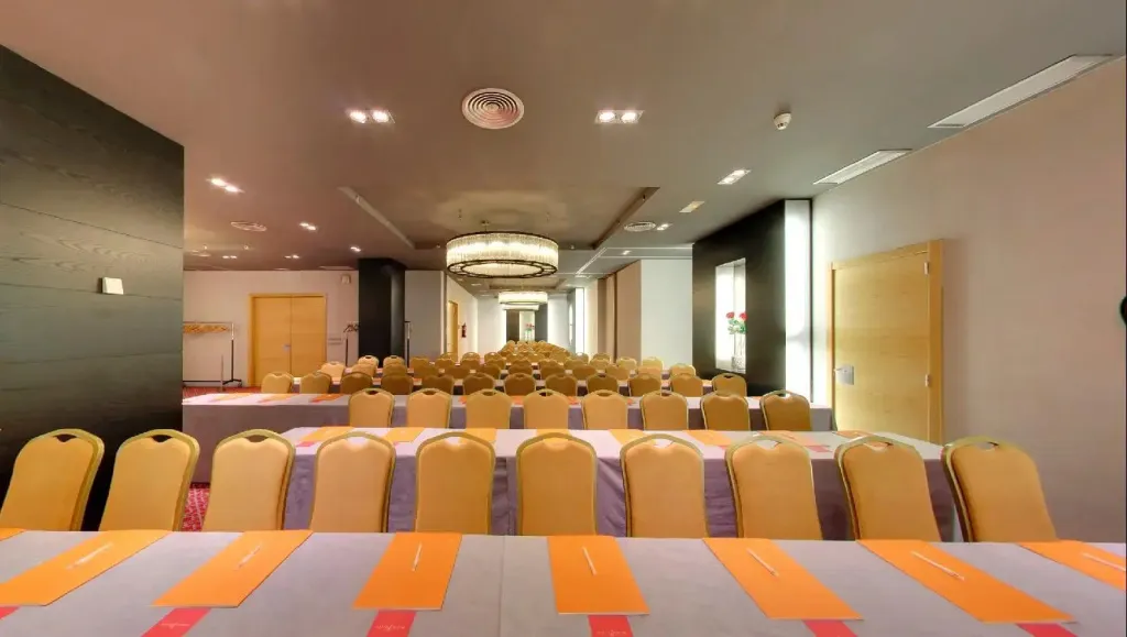 Une grande salle de réunion avec de nombreuses chaises et tables alignées.