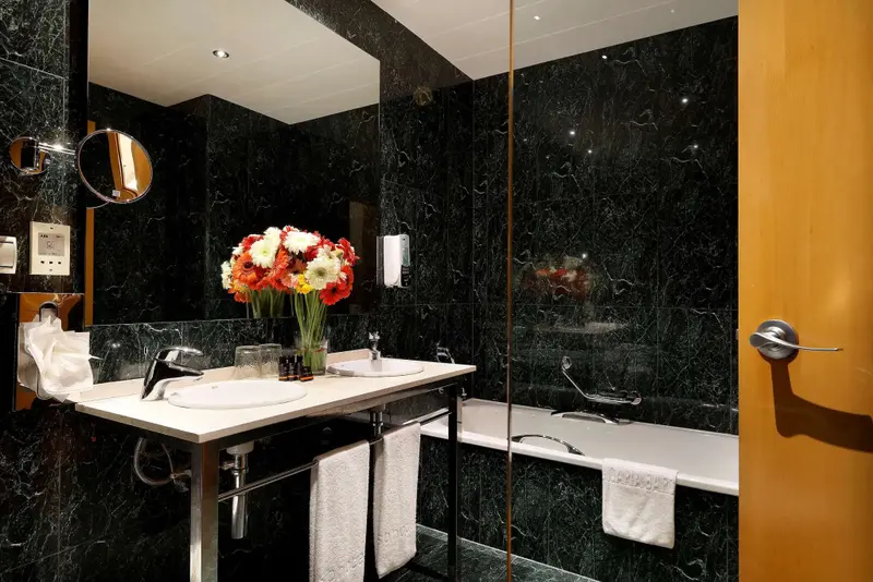 Une salle de bain moderne avec un grand miroir et des fleurs fraîches.