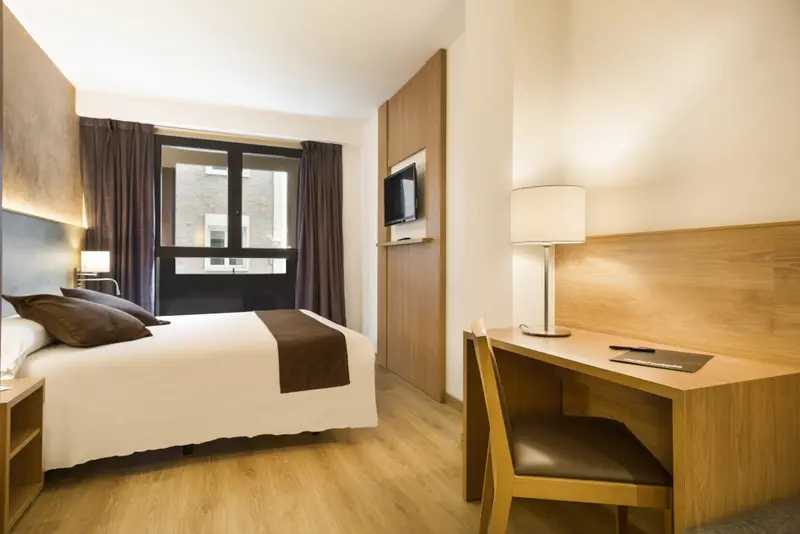 Une chambre lumineuse avec un lit double et un bureau.