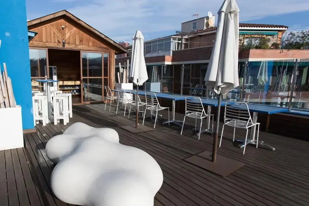 Terrasse aménagée avec tables, chaises et parasols blancs sur une plateforme en bois.