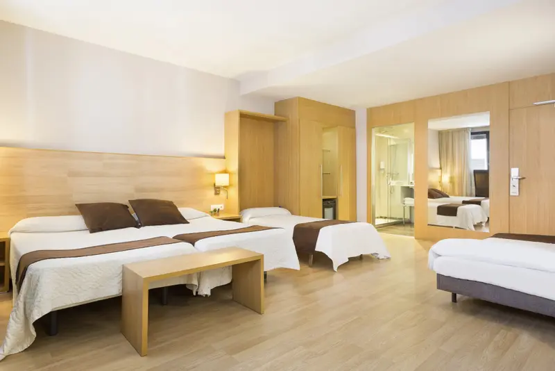 Une chambre lumineuse avec plusieurs lits et un espace détente.