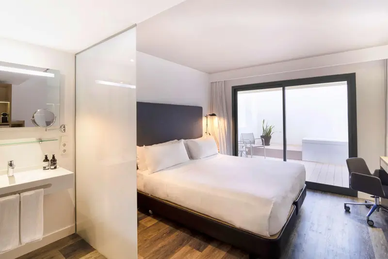 Une chambre lumineuse avec un grand lit et un accès à une terrasse.