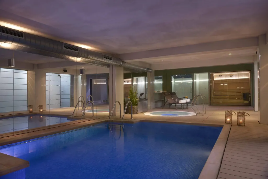 Une piscine intérieure lumineuse avec des transats et un espace détente.