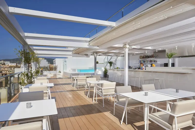 Terrasse aménagée avec tables, chaises et un bar en fond.