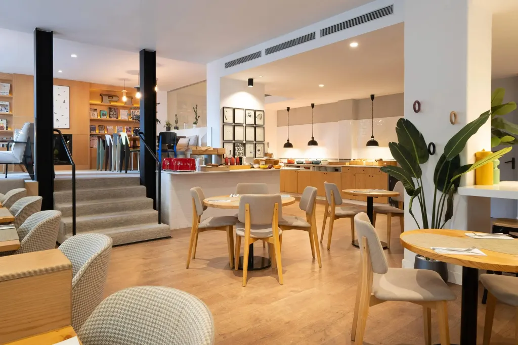Une salle lumineuse avec des tables et des chaises pour les repas.