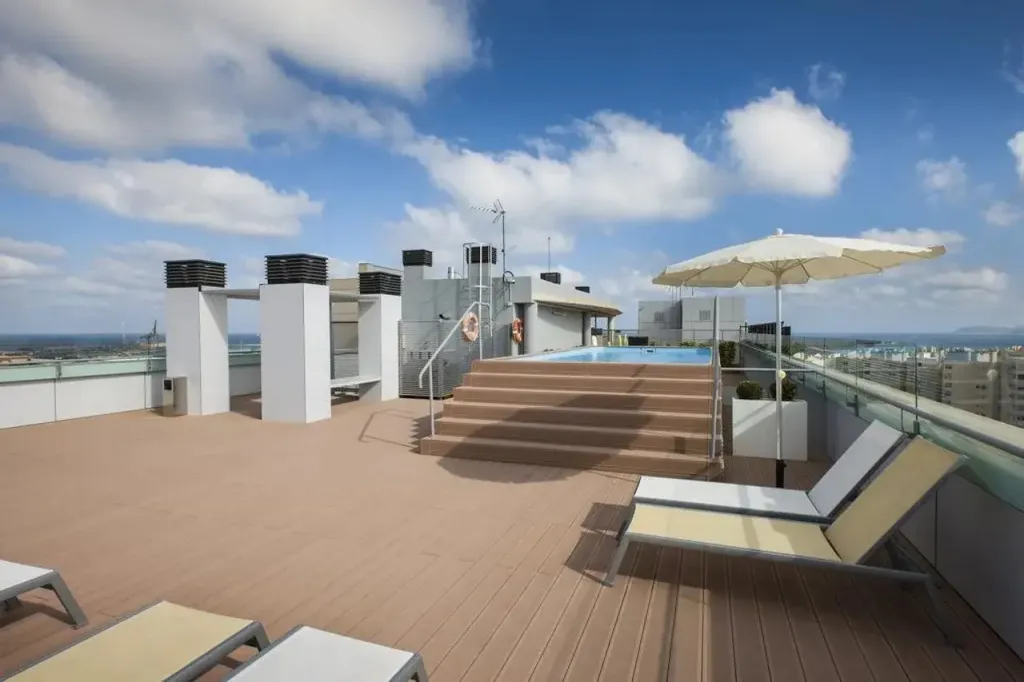 Terrasse avec transats et petite piscine sur toit d'immeuble.