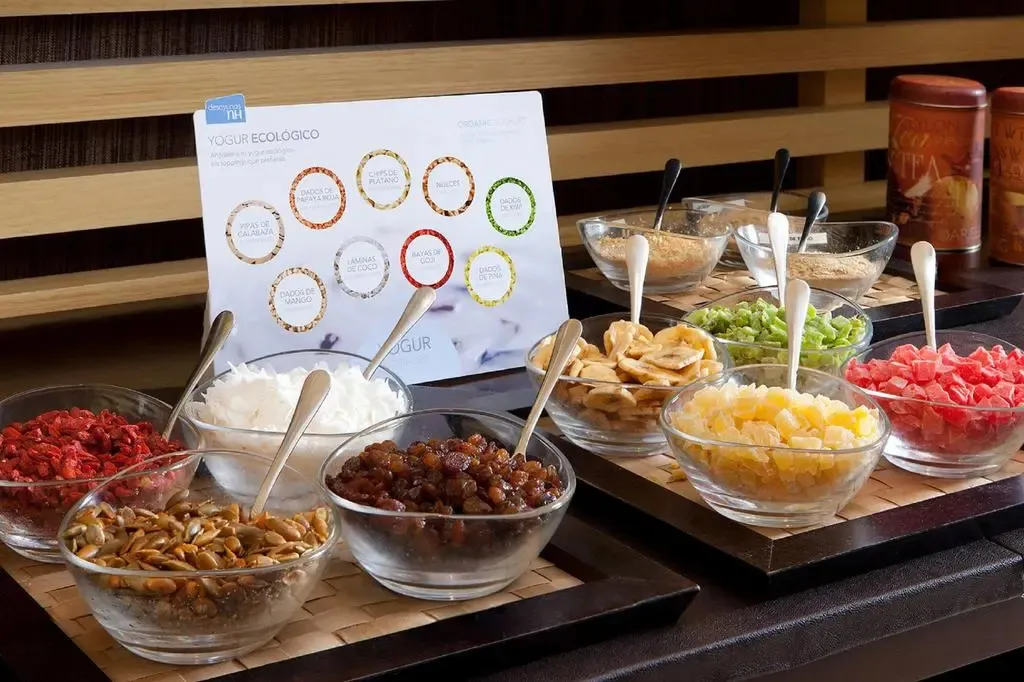 Un buffet propose des yaourts et diverses garnitures colorées.