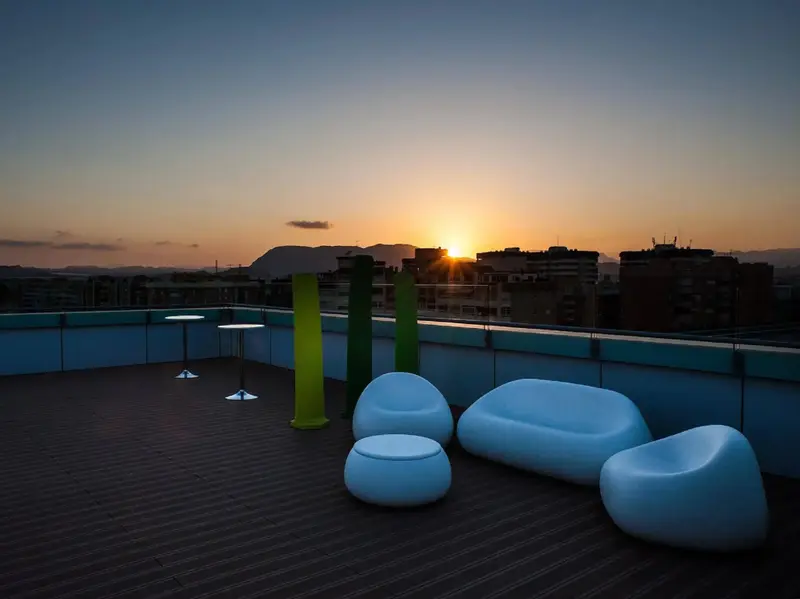 Terrasse aménagée avec mobilier design et vue sur la ville au coucher du soleil.