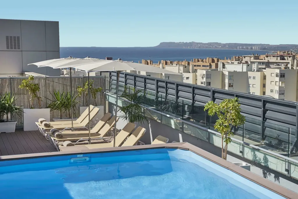 Terrasse avec piscine et vue sur la mer et la ville.