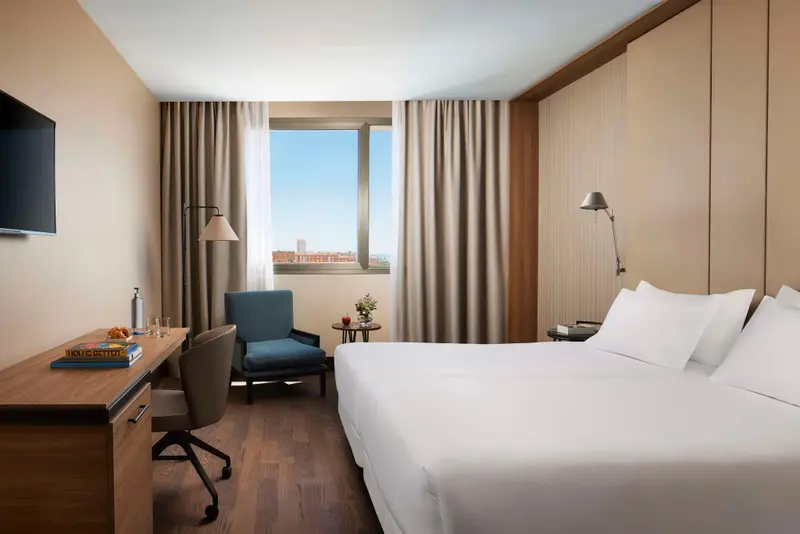 Une chambre lumineuse avec un lit et un espace de travail près d'une fenêtre.