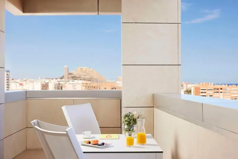 Une table avec un petit-déjeuner est mise en scène sur un balcon avec vue sur la ville.