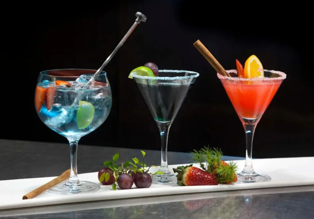 Trois cocktails colorés sont présentés sur un comptoir brillant.