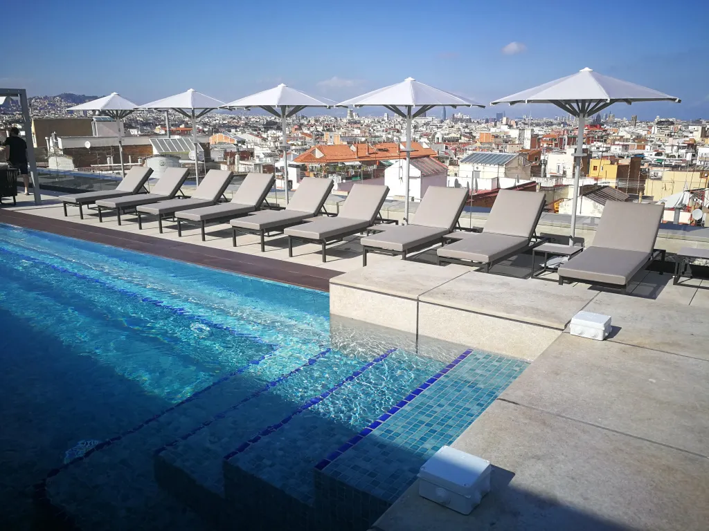 Terrasse avec transats et piscine au bord d'une ville.
