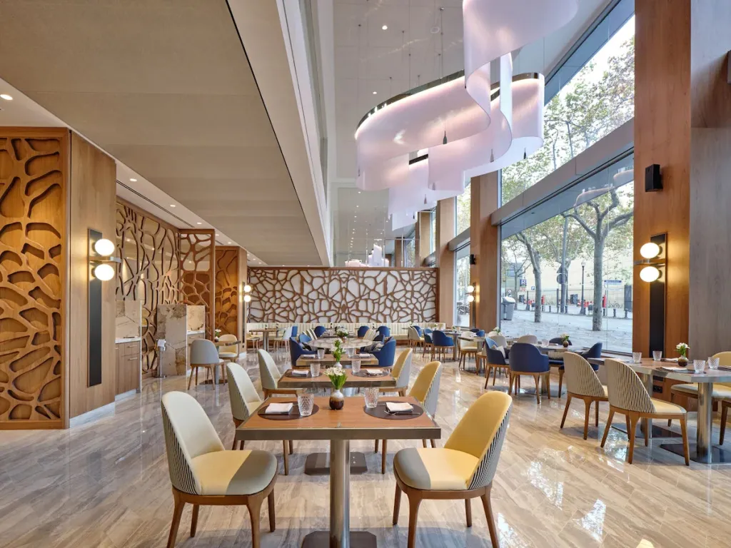 Une salle lumineuse avec des tables dressées et des chaises confortables.