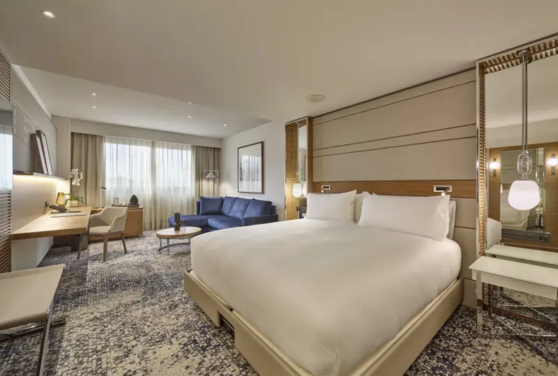 Une chambre lumineuse avec un grand lit et un coin salon.