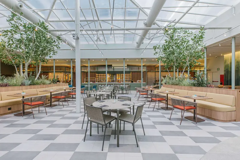 Une salle lumineuse avec des tables et des chaises disposées sur un sol à carreaux.