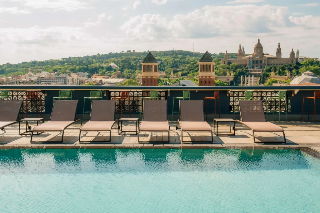 Transats alignés au bord d'une piscine avec vue sur une ville.