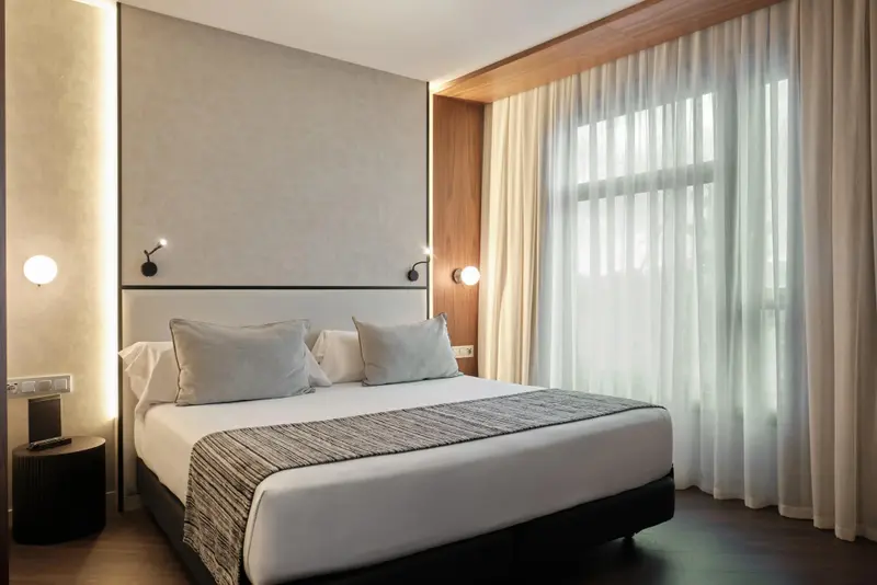 Une chambre lumineuse avec un grand lit et des rideaux blancs.