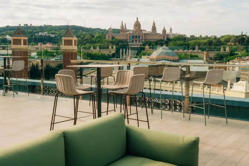 Terrasse aménagée avec tables hautes et canapés offrant une vue sur la ville.
