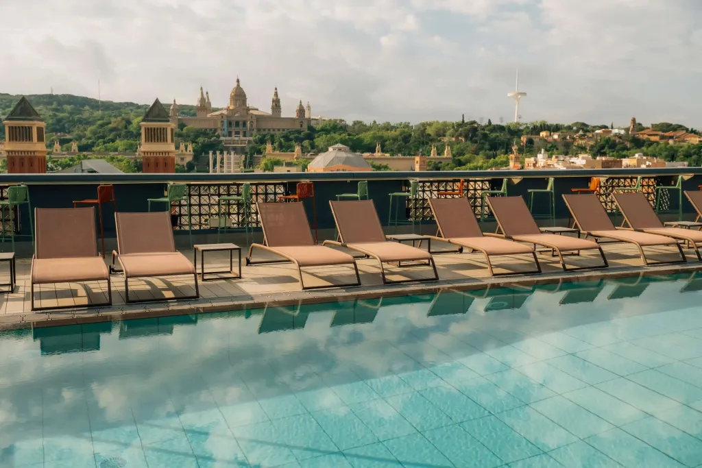 Transats alignés au bord d'une piscine avec vue sur une ville.