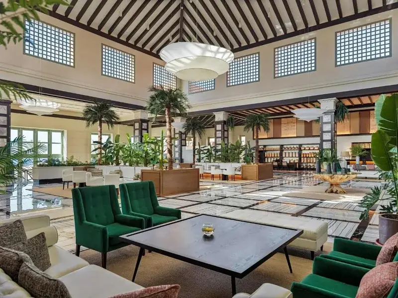 Vaste hall d'accueil avec mobilier design et plantes tropicales.