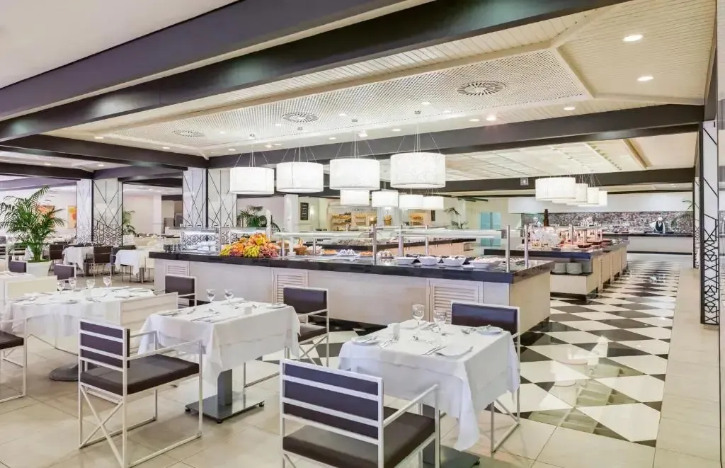 Une salle de restaurant lumineuse avec des tables dressées et un buffet garni.
