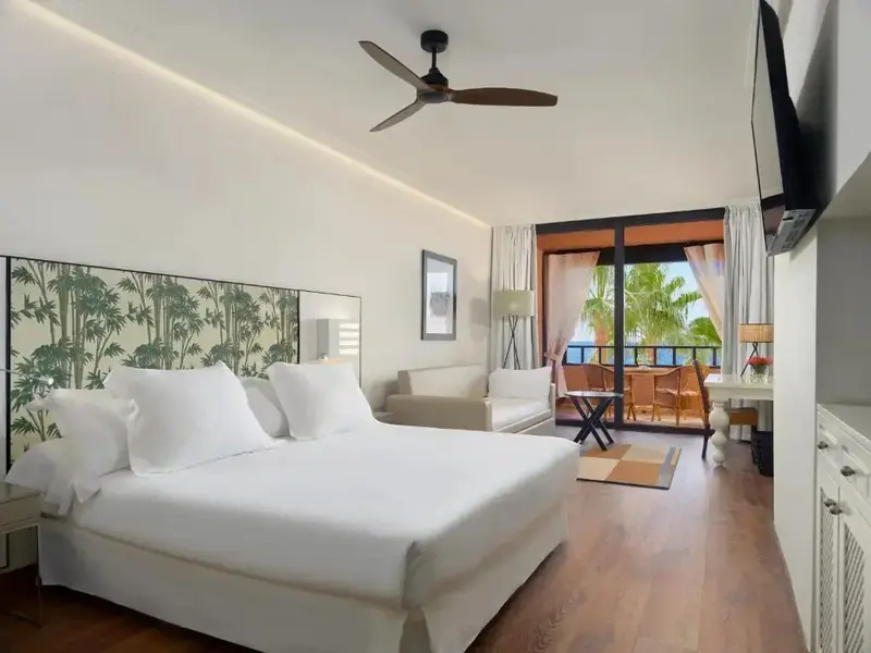 Une chambre lumineuse avec un grand lit et un accès à un balcon.