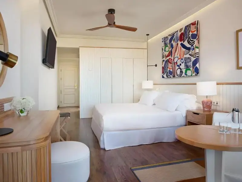 Une chambre lumineuse avec un grand lit et un coin repas.
