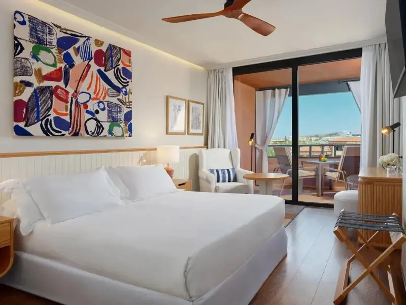 Une chambre lumineuse avec un grand lit et un accès à un balcon.