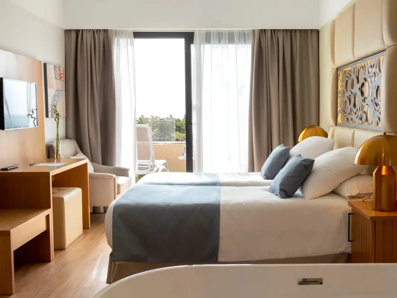Une chambre lumineuse avec deux lits simples et un accès à un balcon.