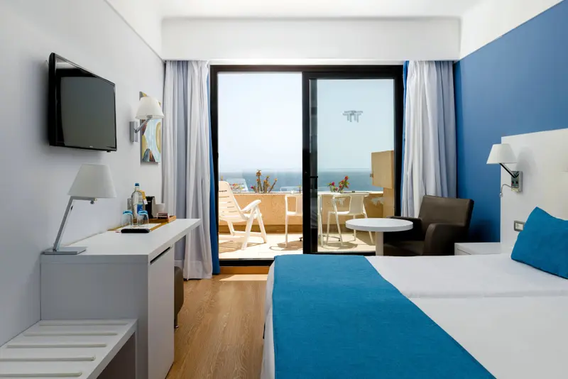 Une chambre lumineuse s'ouvre sur une terrasse avec vue sur la mer.