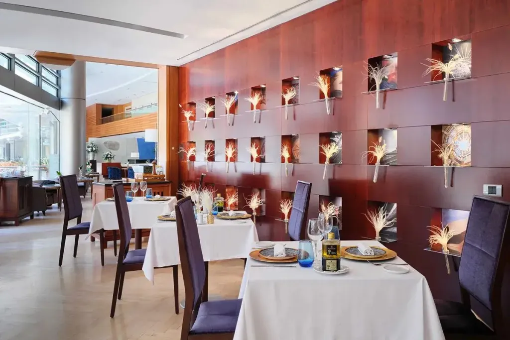 Une salle de restaurant lumineuse avec des tables nappées et une décoration murale originale.