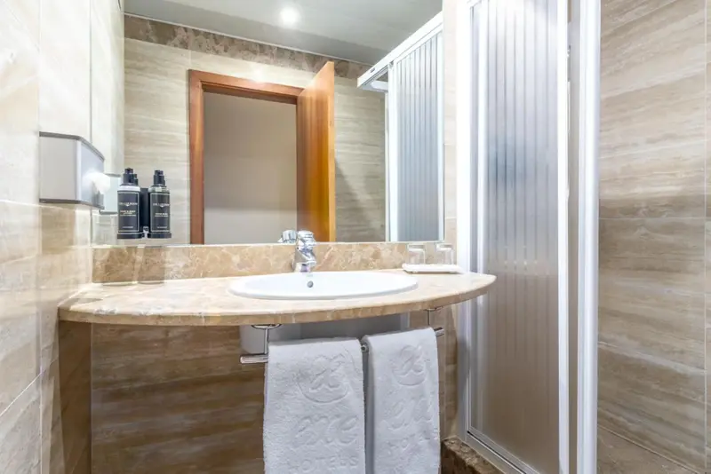 Une salle de bain claire avec un lavabo et une douche vitrée.
