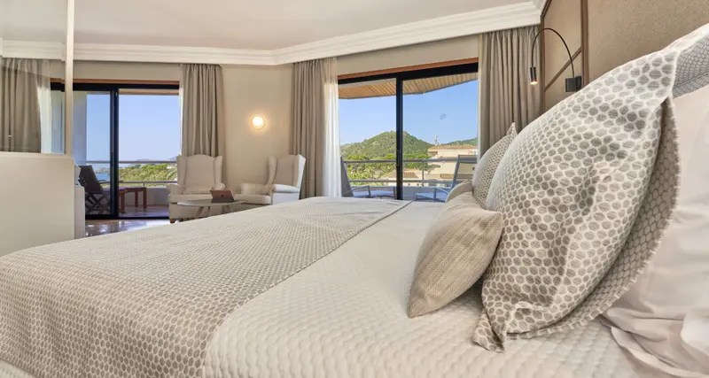 Une chambre lumineuse avec un grand lit donnant sur une vue dégagée.