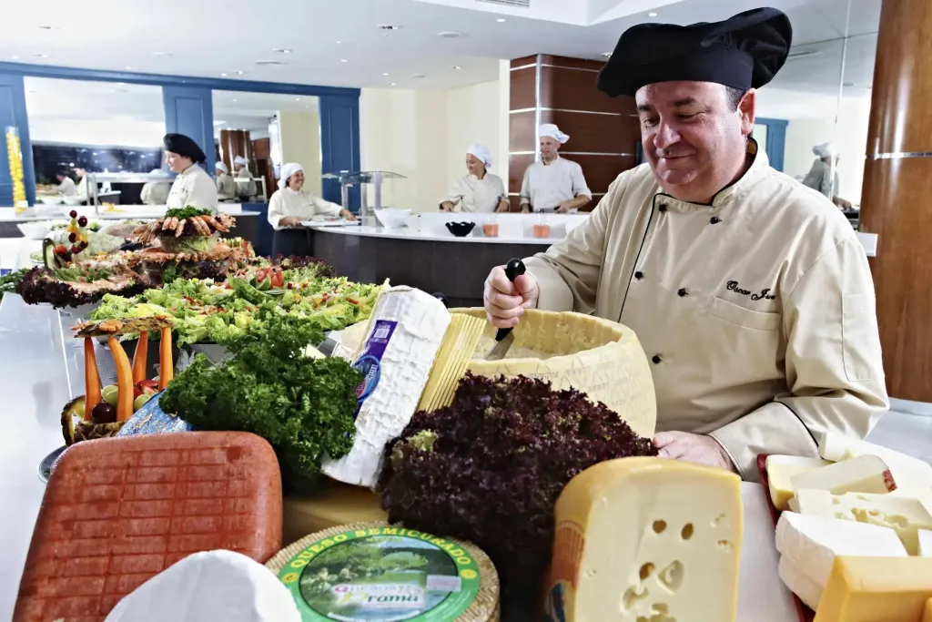 Un chef prépare un plateau de fromages variés dans un espace de restauration.