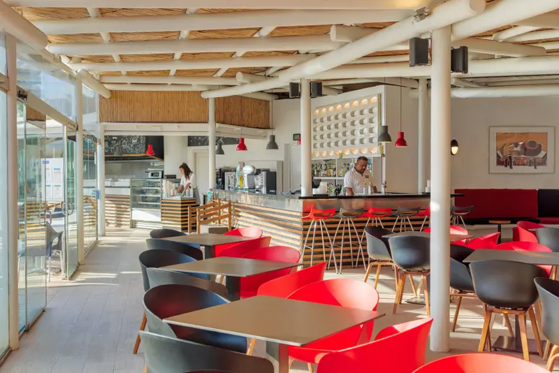 Une salle lumineuse avec un comptoir de bar et des tables à manger.