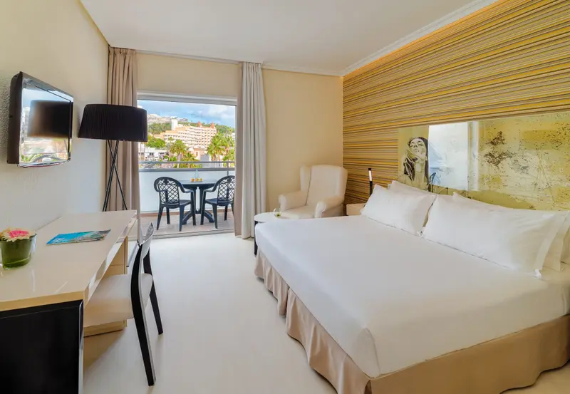Une chambre lumineuse avec un grand lit et un accès à un balcon.