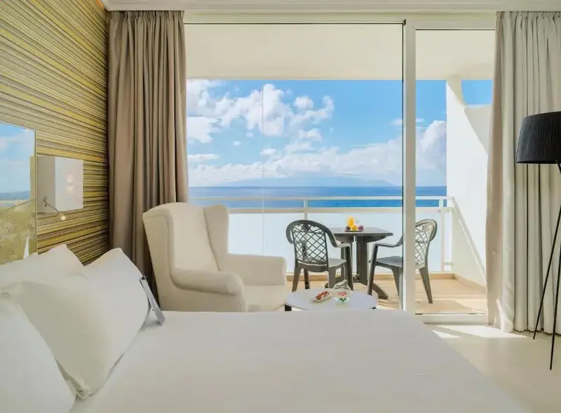 Une chambre lumineuse s'ouvre sur une terrasse avec vue sur la mer.