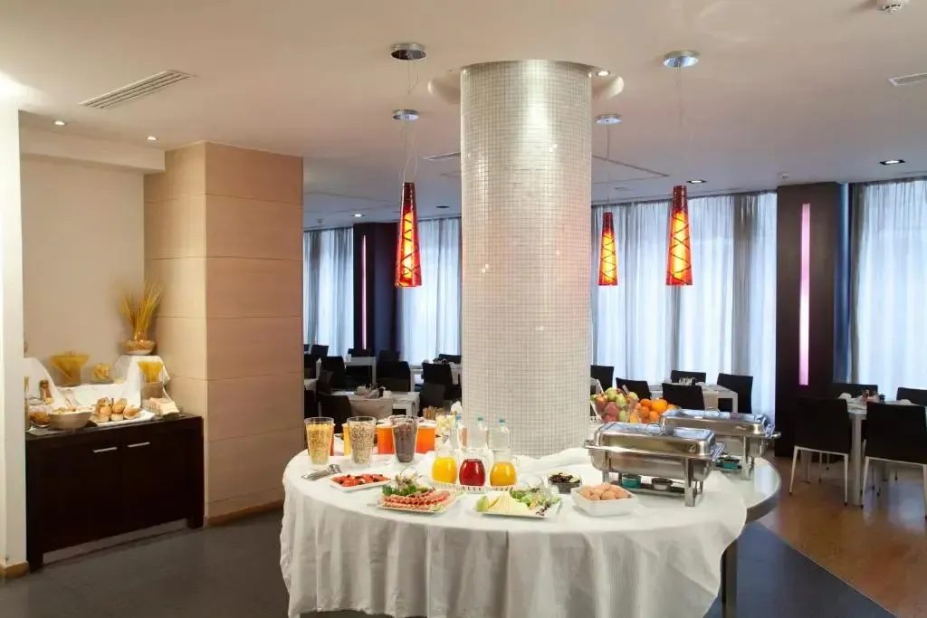 Un buffet propose des fruits, des pâtisseries et des boissons dans une salle lumineuse.